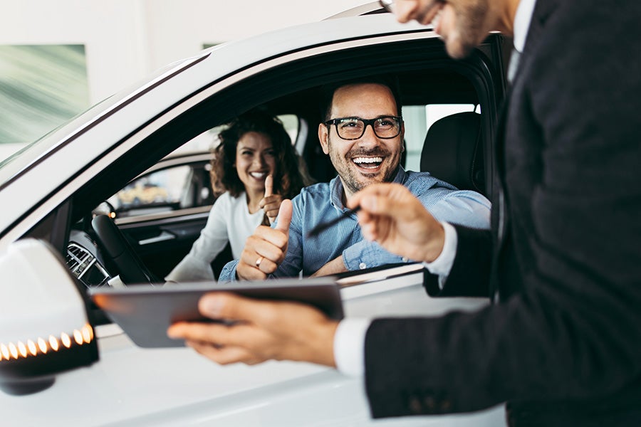couple in car with salesman holding tablet